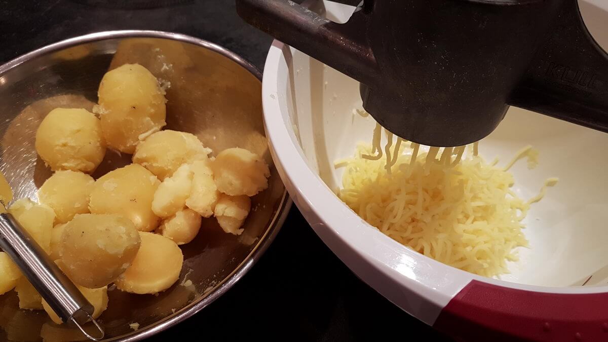 Kartoffeln durch eine Kartoffelpresse drücken