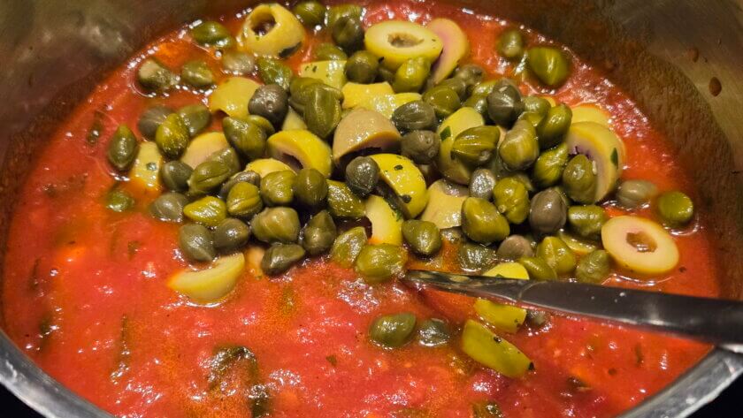 Oliven zusammen mit den Kapern der Arrabbiata-Sauce zufügen