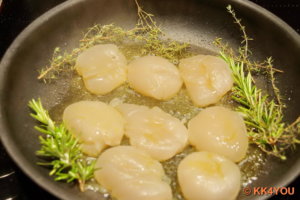 Jakobsmuscheln mit Thymian und Rosmarin in einer Pfanne von jeder Seite braten